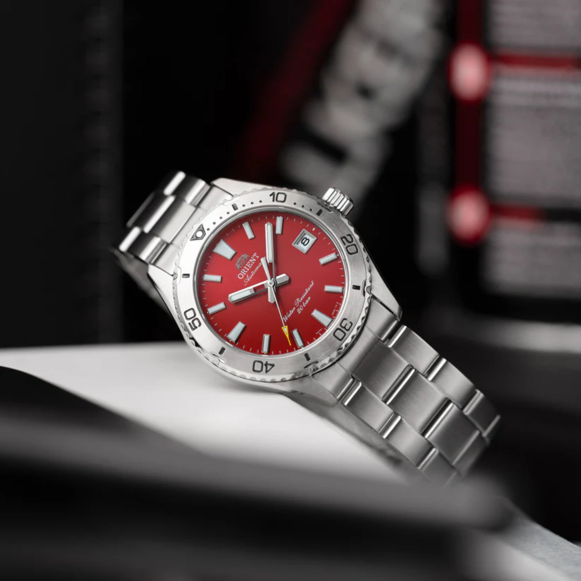 An Orient Mako automatic dive watch featuring a vibrant red dial and a stainless steel bracelet