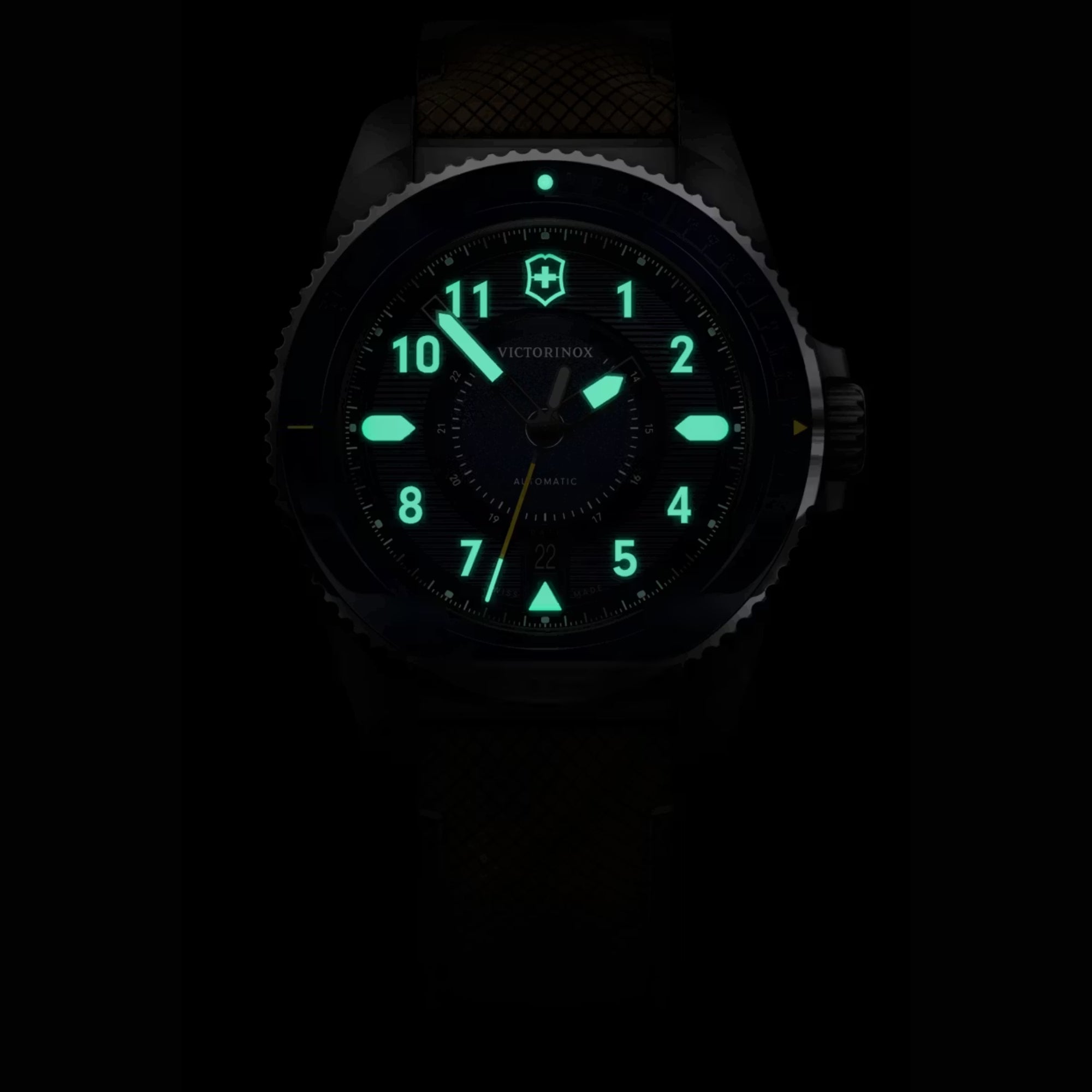 Victorinox automatic watch with its hands, logo, and hour markers glowing brightly in green lume