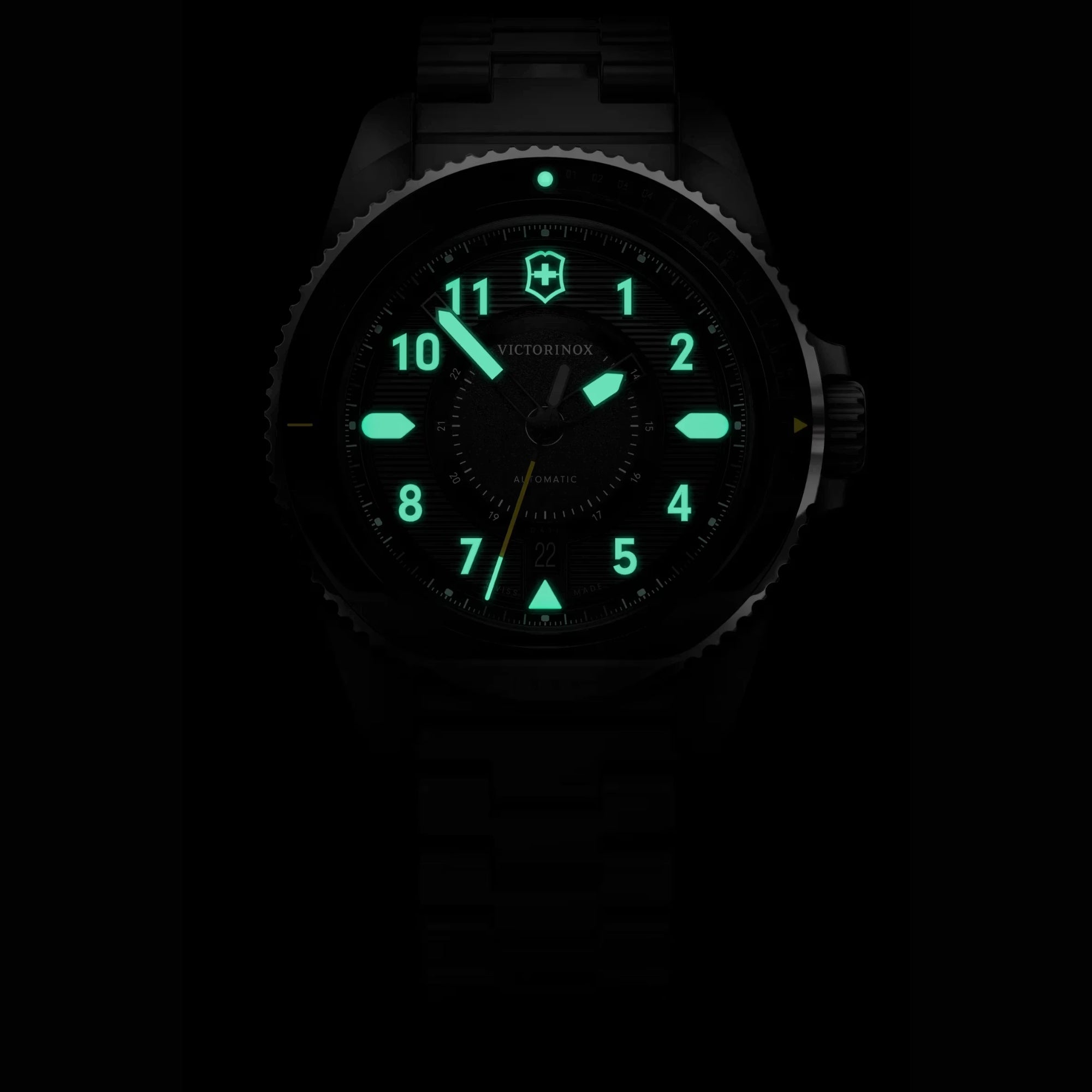 Victorinox automatic watch with its hands and hour markers glowing brightly in green lume