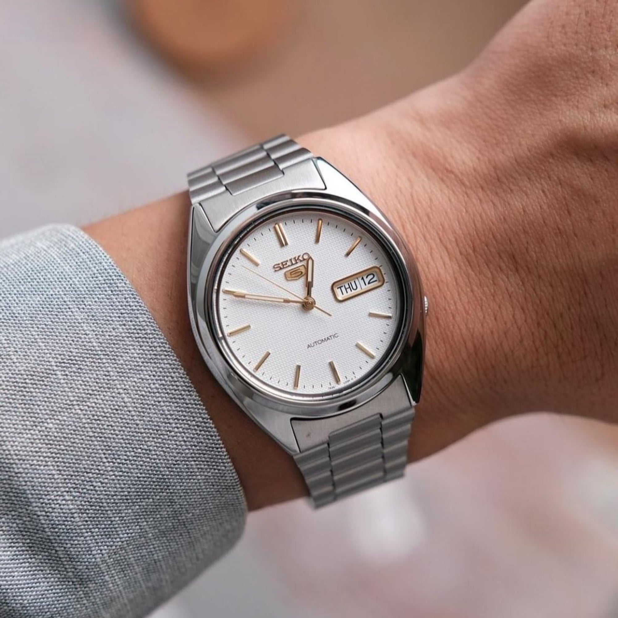 Seiko 5 Automatic SNXG47K1 white dial watch worn on wrist with stainless steel bracelet