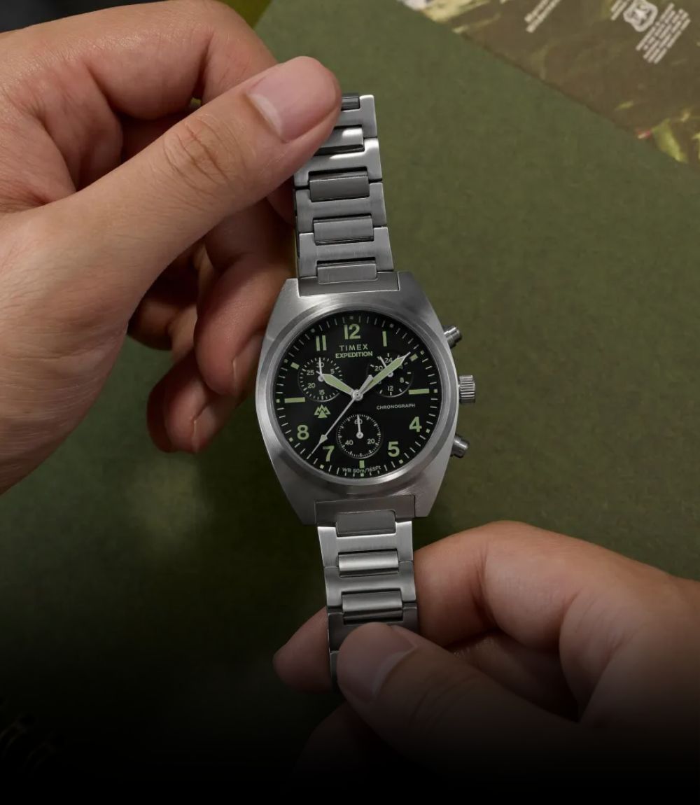 Timex Expedition chronograph field watch with black dial and brushed stainless steel bracelet held in hands