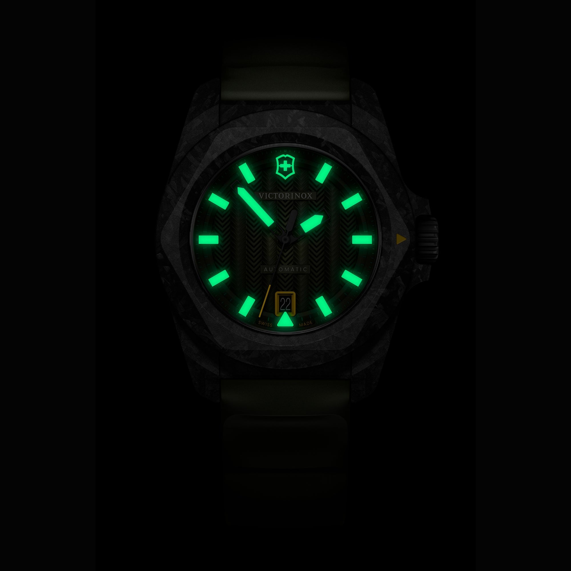 Close-up of a Victorinox automatic watch at night, featuring green glowing lume