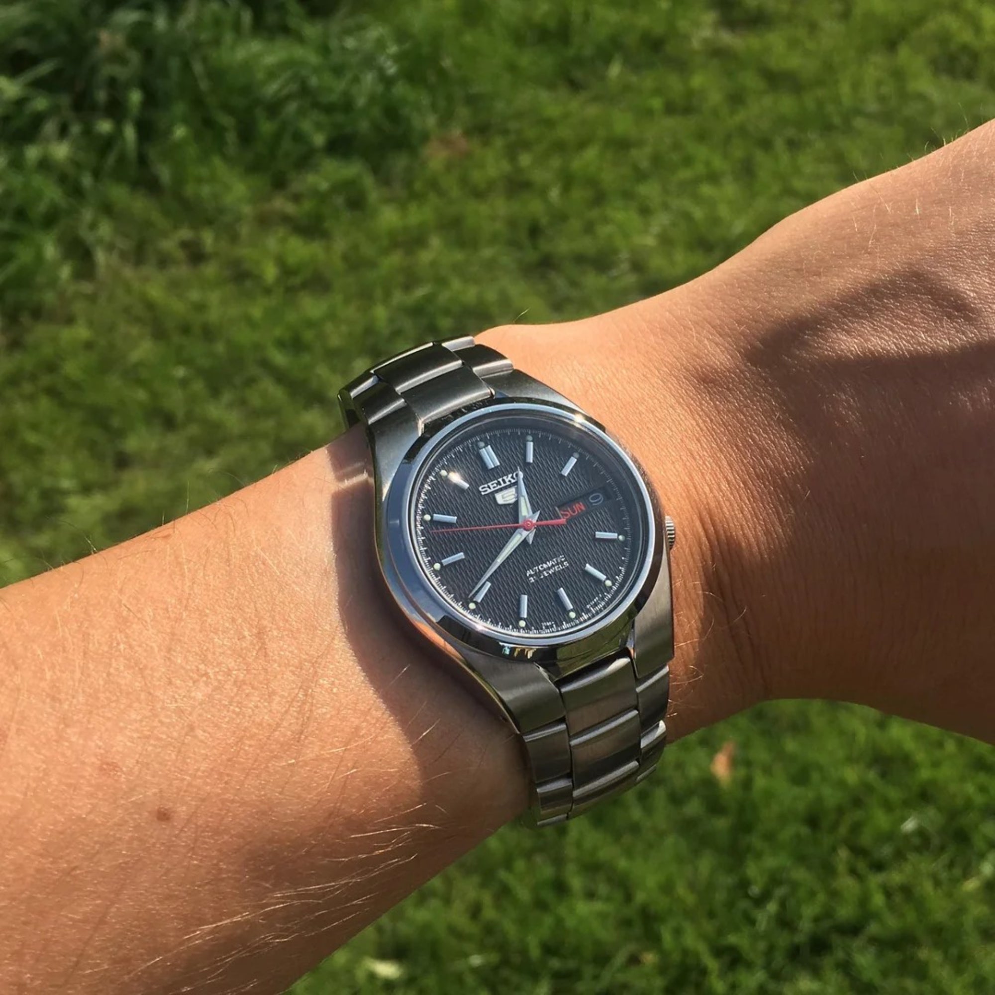 Seiko 5 automatic black dial stainless steel watch on wrist