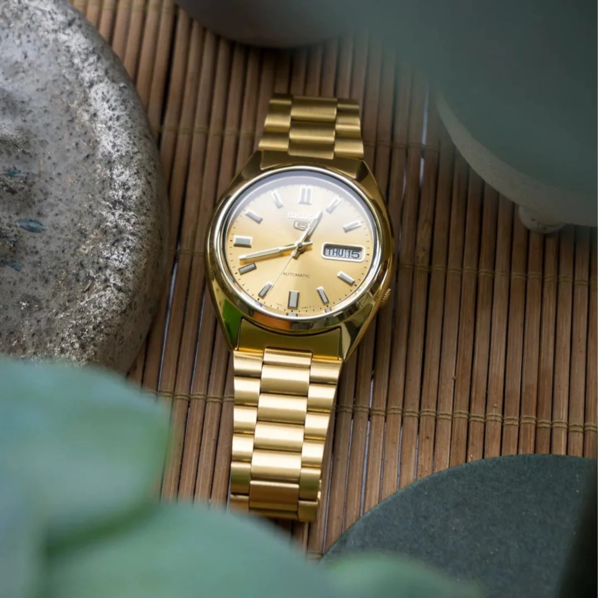 Seiko 5 automatic SNXS80K1 gold dial watch on wooden surface