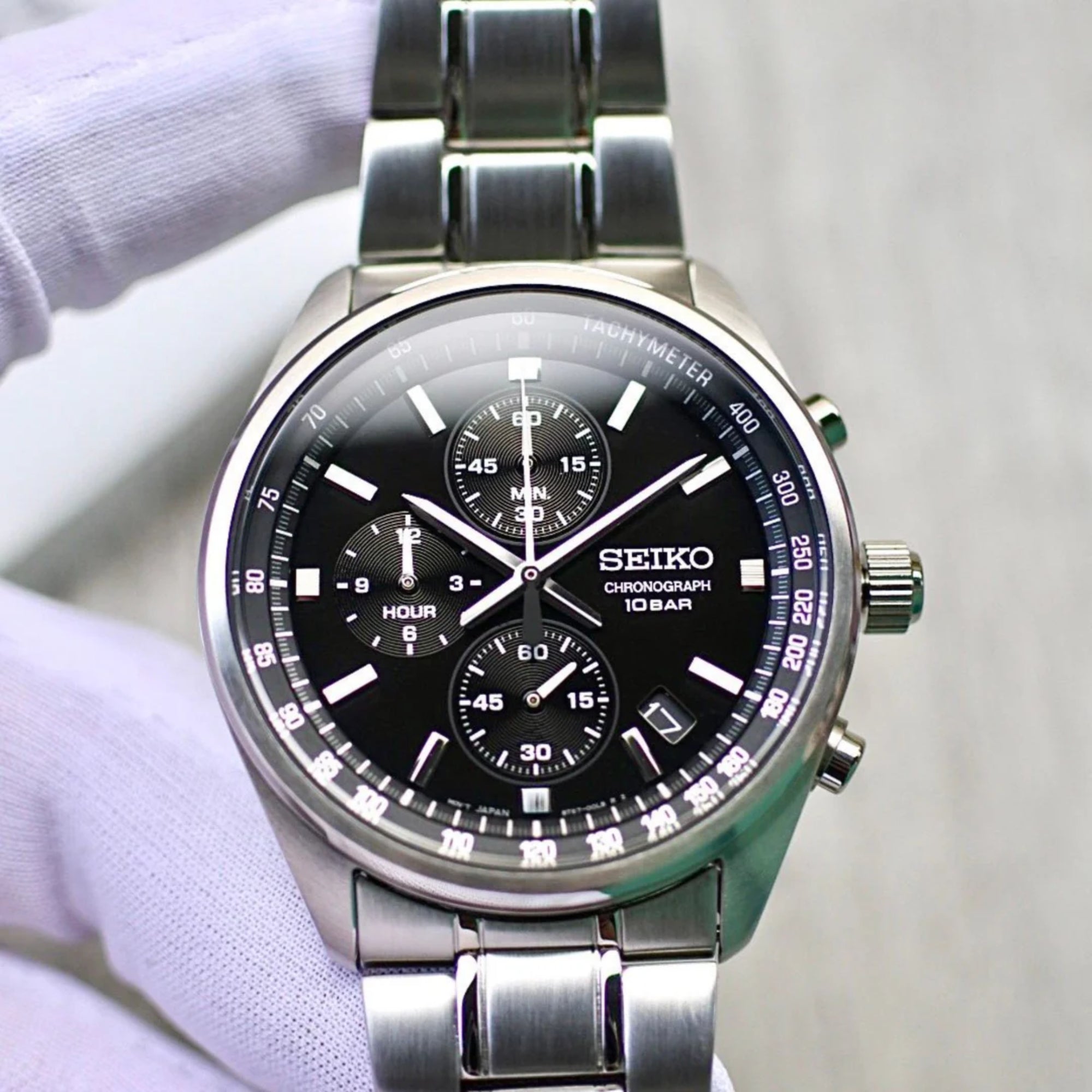 Seiko watch with black dial and silver metal band on a white background