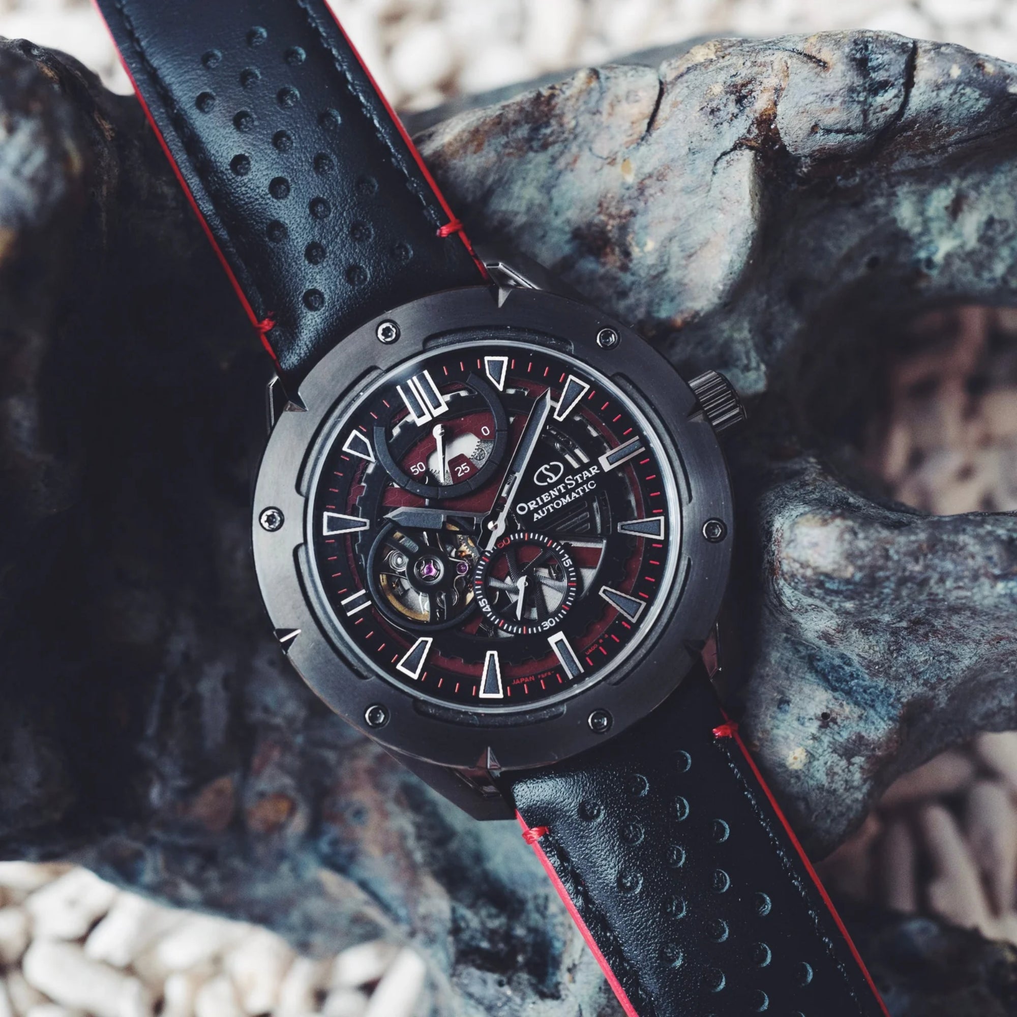 Orient Star Avant-Garde RE-AV0A03B00B black skeleton automatic watch placed on dark rock surface