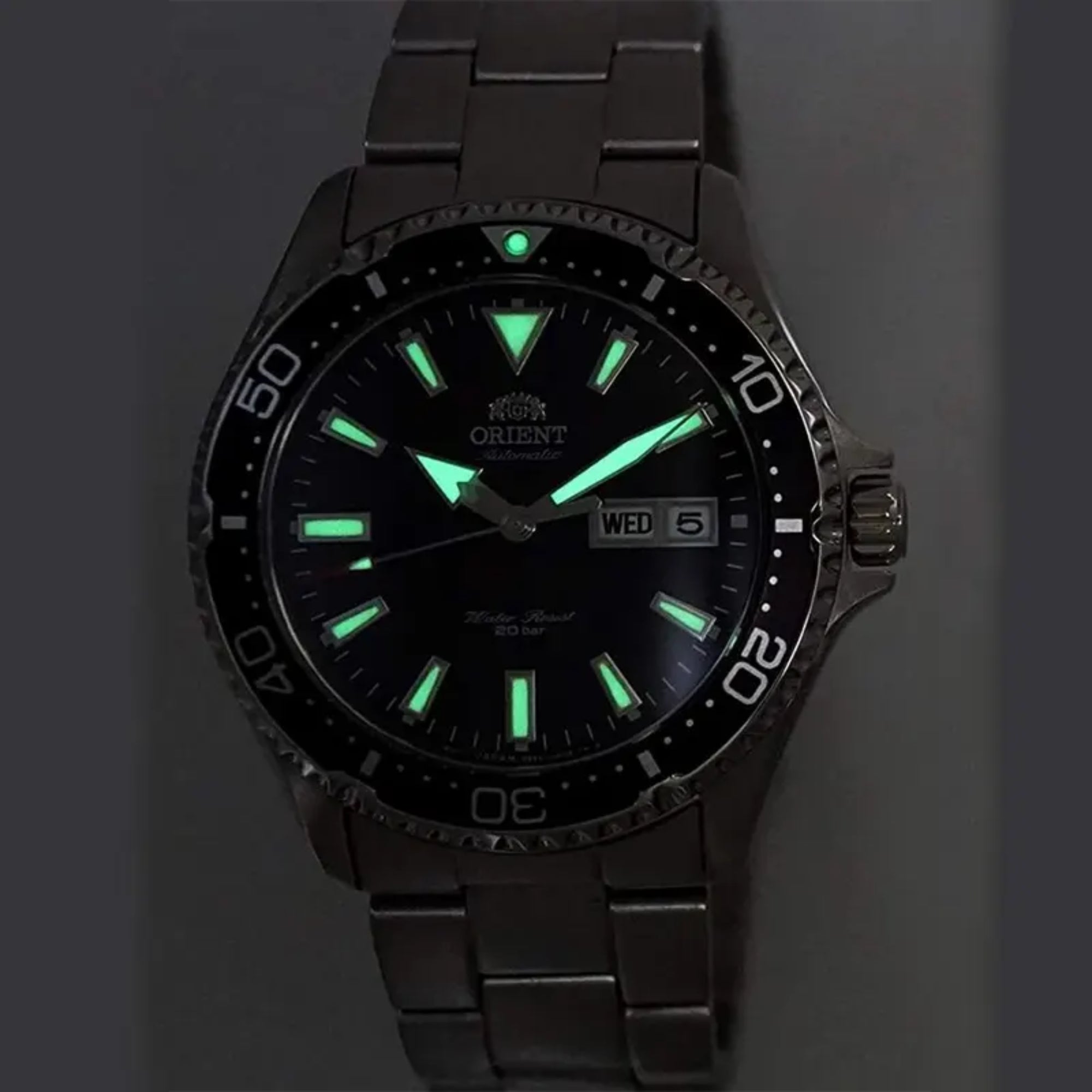 Glowing green luminous hands and markers on an Orient Mako watch dial in the dark