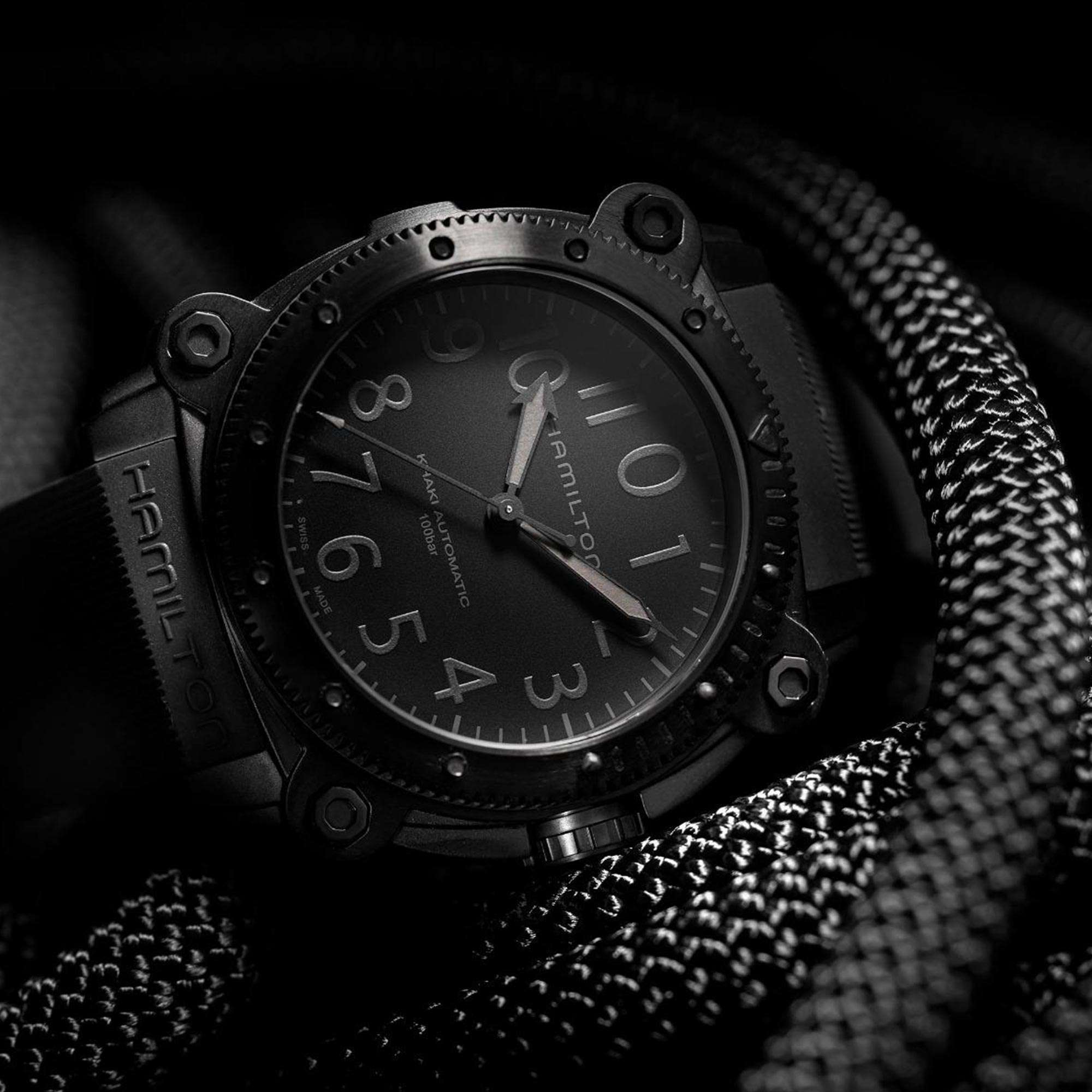 Close-up of Hamilton Khaki Automatic black dial dive watch with large luminous numerals on textured rope background