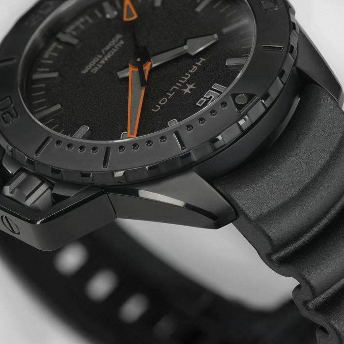 Hamilton H77845330 textured black dial with luminous markers and orange minute hand close-up