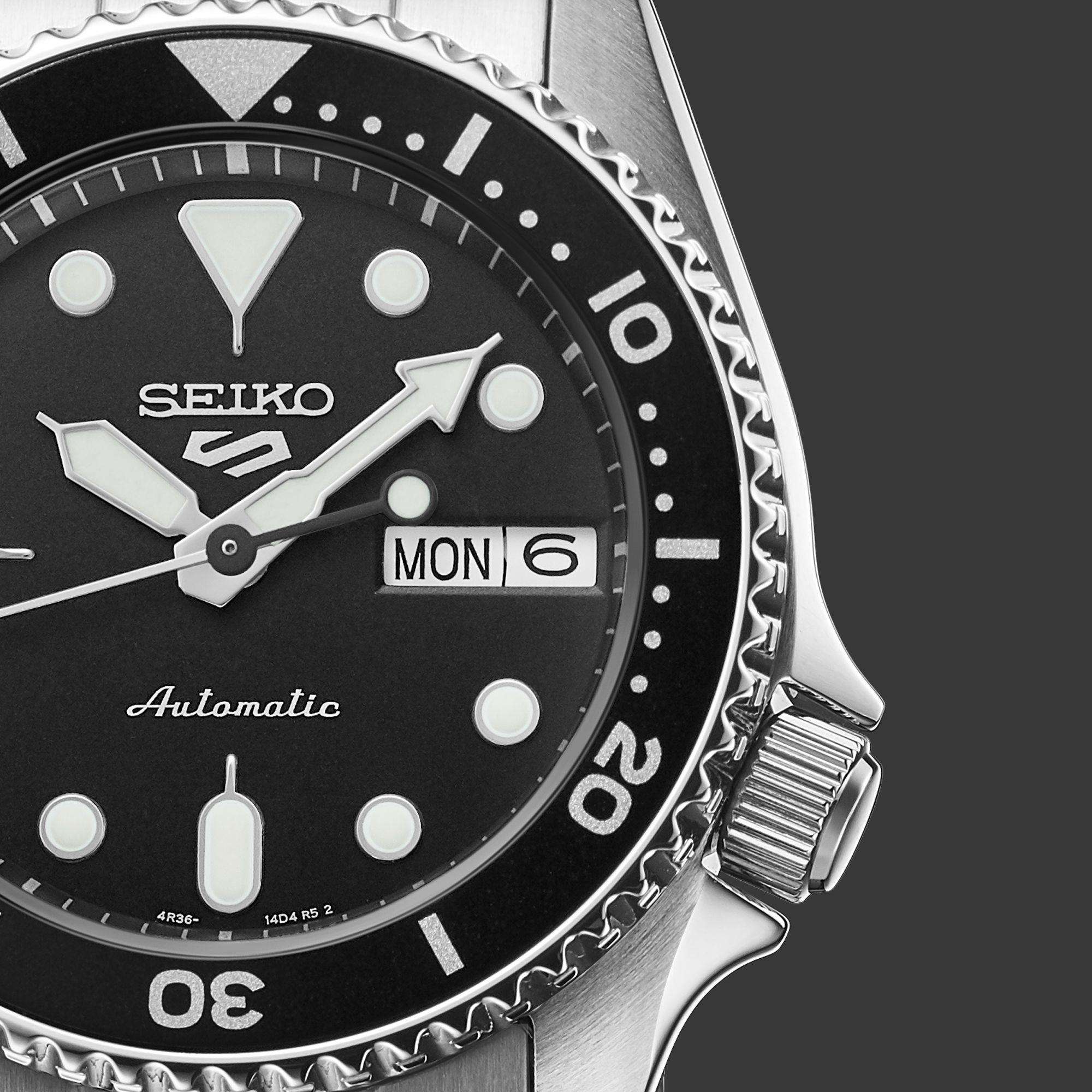 Seiko watch with black dial and silver case on a dark background