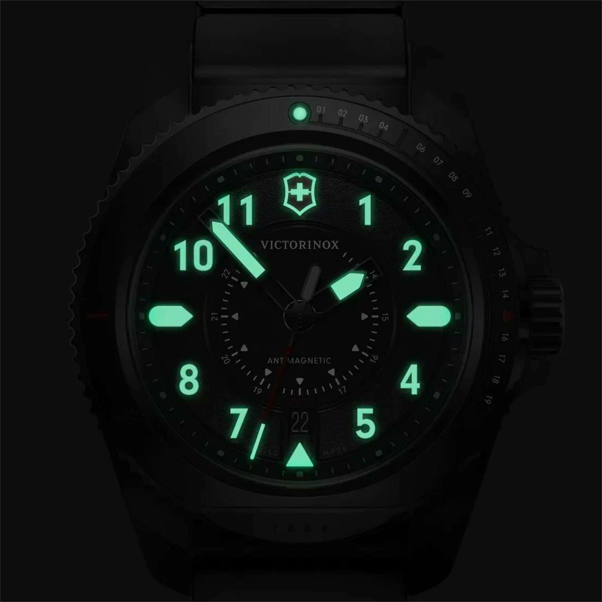 A dark close-up of a Victorinox anti-magnetic watch with its hands, logo, and hour markers glowing brightly in green lume