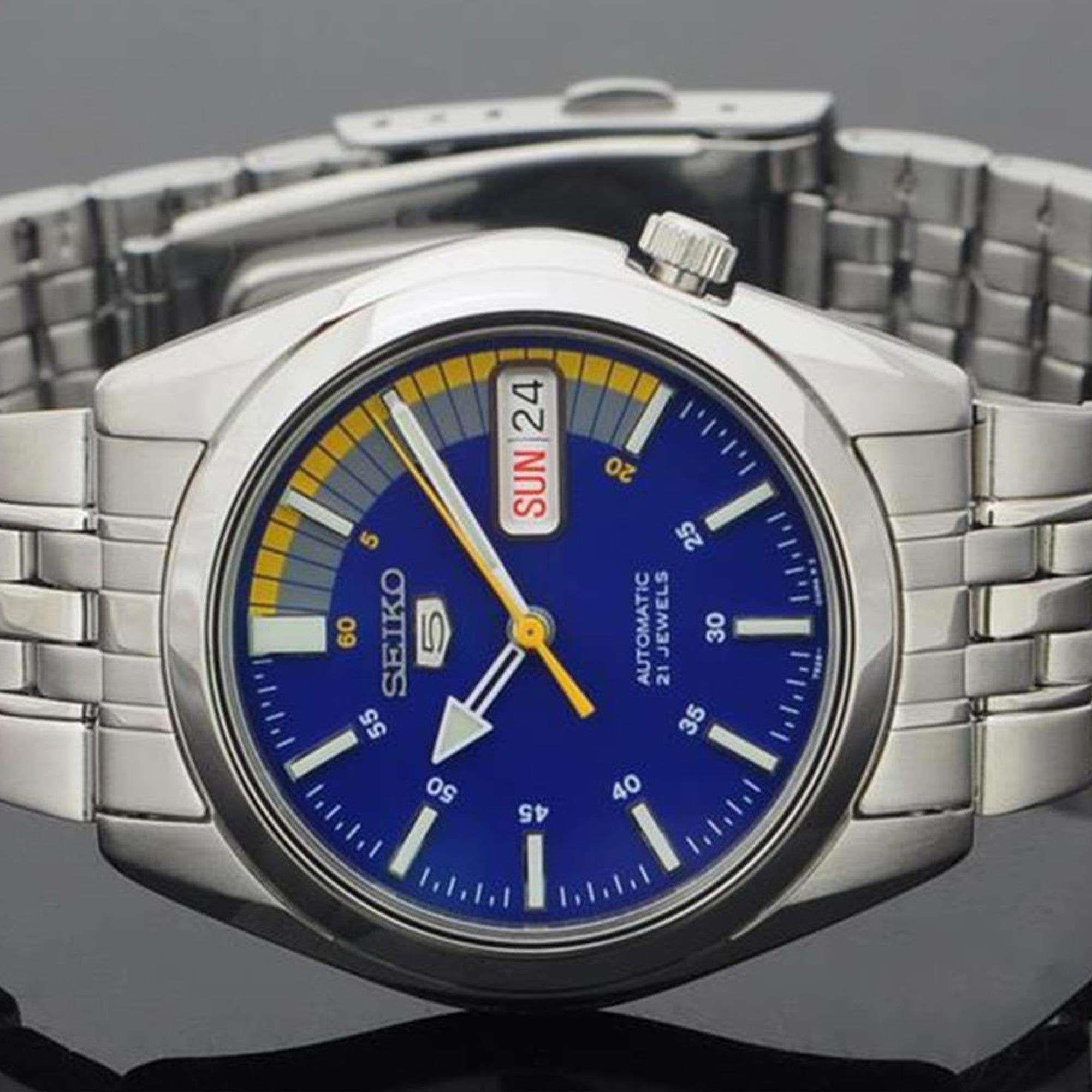 Silver Seiko watch with a blue dial on a reflective surface