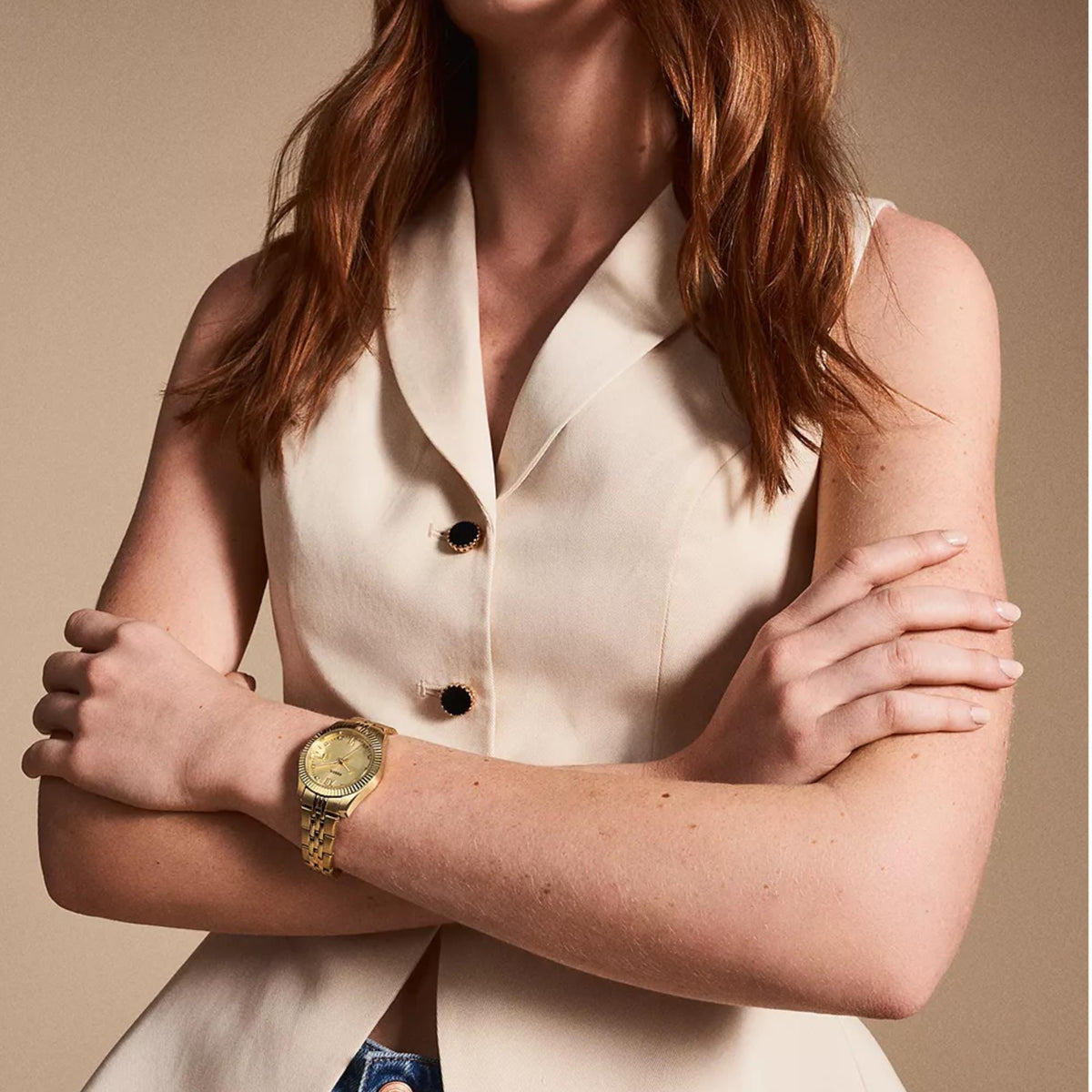 On-wrist view of the Fossil Scarlette ES5338 ladies timepiece showcasing the gold dial and gold-tone steel bracelet styled with a cream waistcoat
