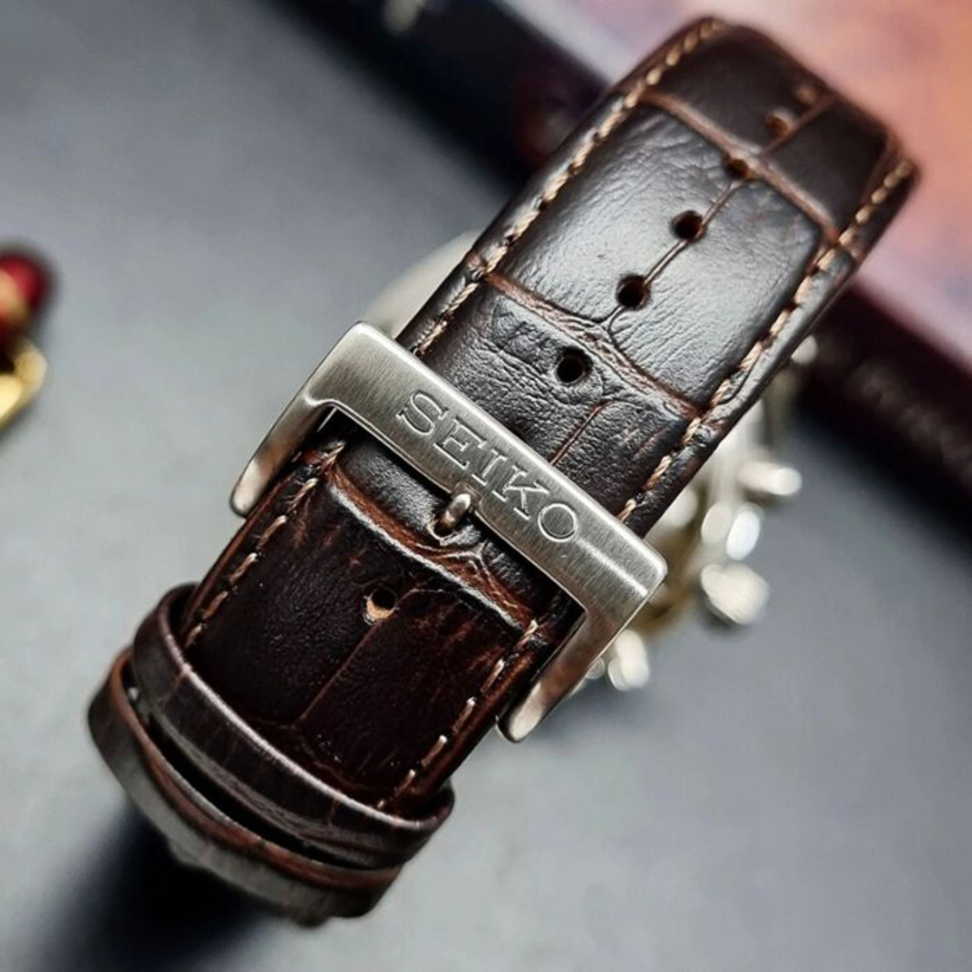 Close-up of Seiko engraved stainless steel buckle on brown leather strap