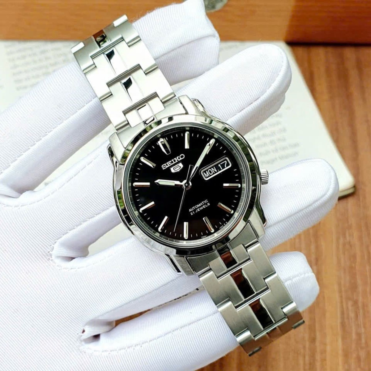 Seiko 5 Automatik Herrenarmbanduhr mit schwarzem Zifferblatt und Stahlarmband SNKK71K1