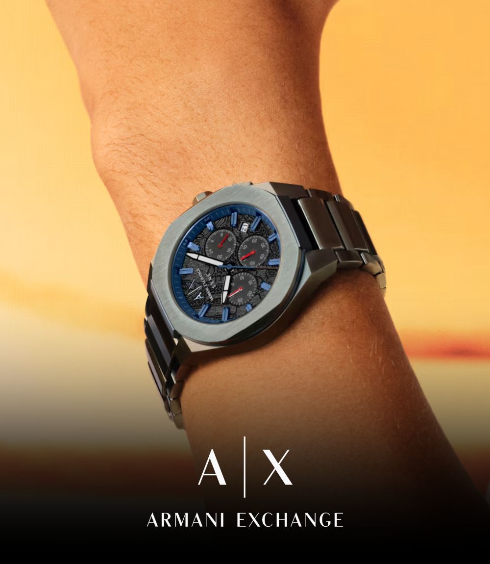 Close-up of an Armani Exchange chronograph watch worn on a wrist, featuring an octagonal stainless steel case, dark textured dial with blue and red accents, featuring the A|X logo at the bottom
