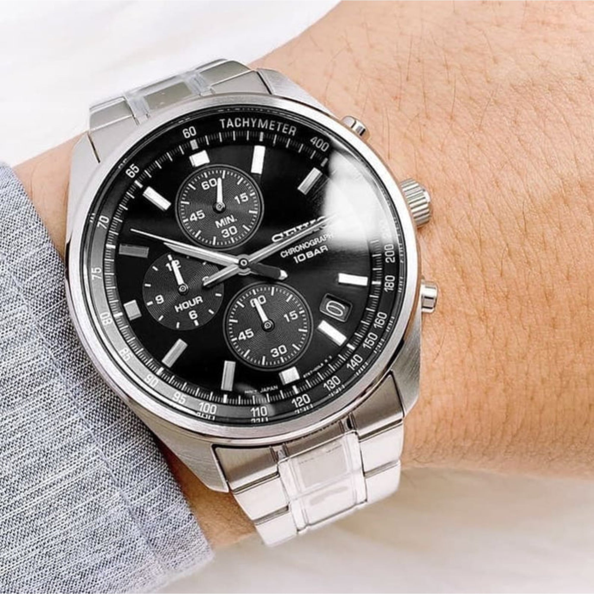 Silver watch with black dial on a wrist, brand 'Citizen' visible