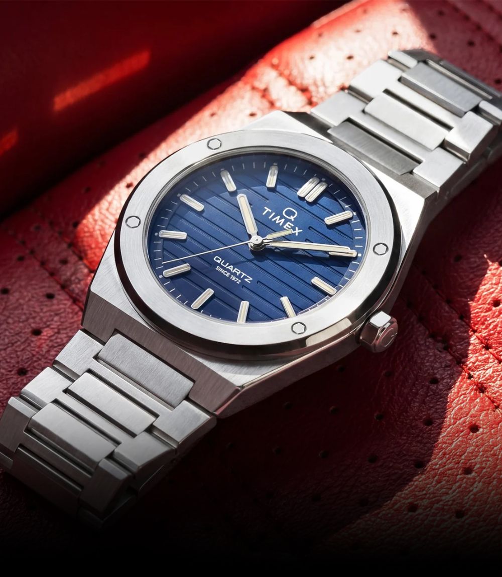 Timex Q Essential quartz watch featuring a blue dial with a steel case and integrated stainless steel bracelet