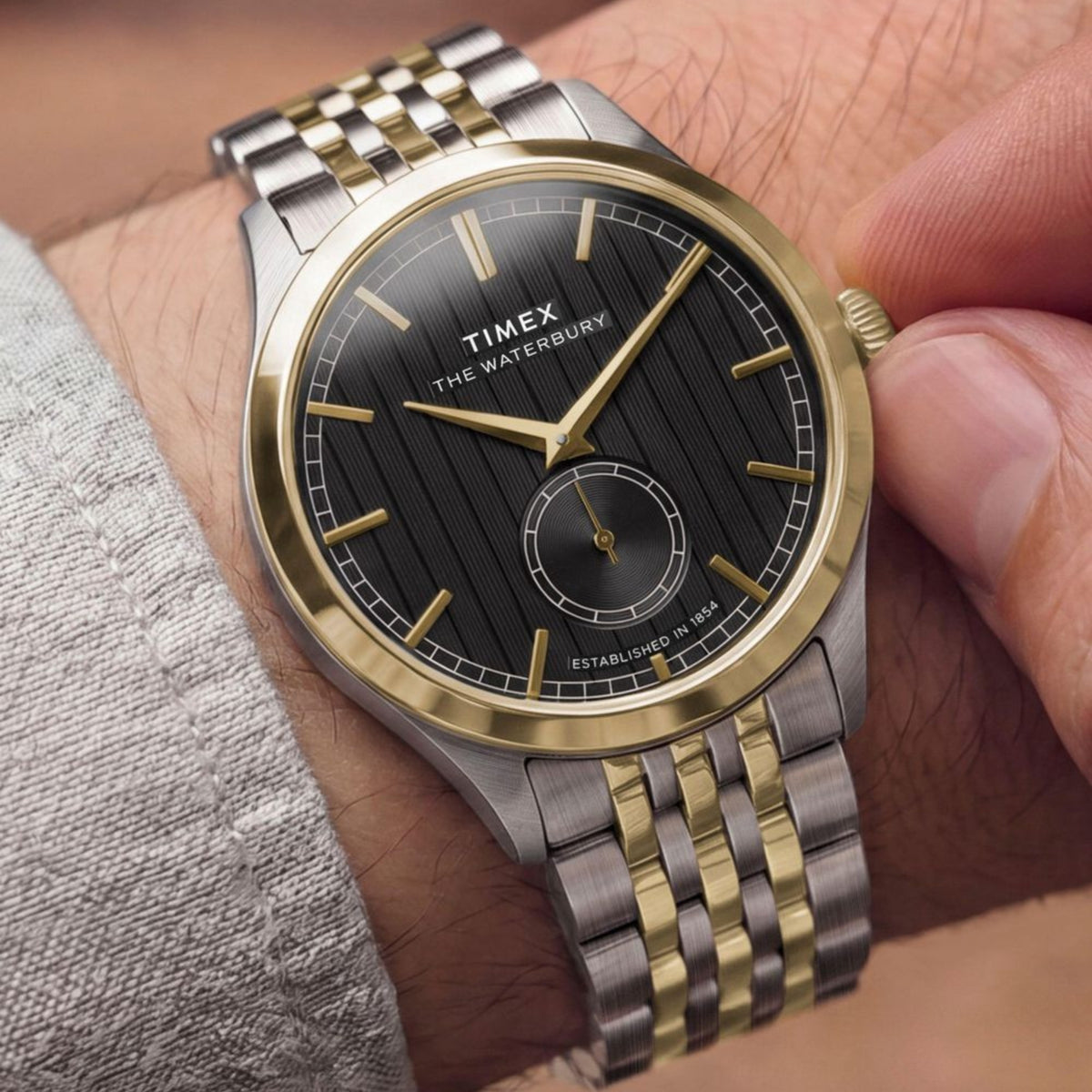 Timex Waterbury TW2Y91900 wrist view showing a black dial quartz watch styled on a person wearing a two-tone steel bracelet