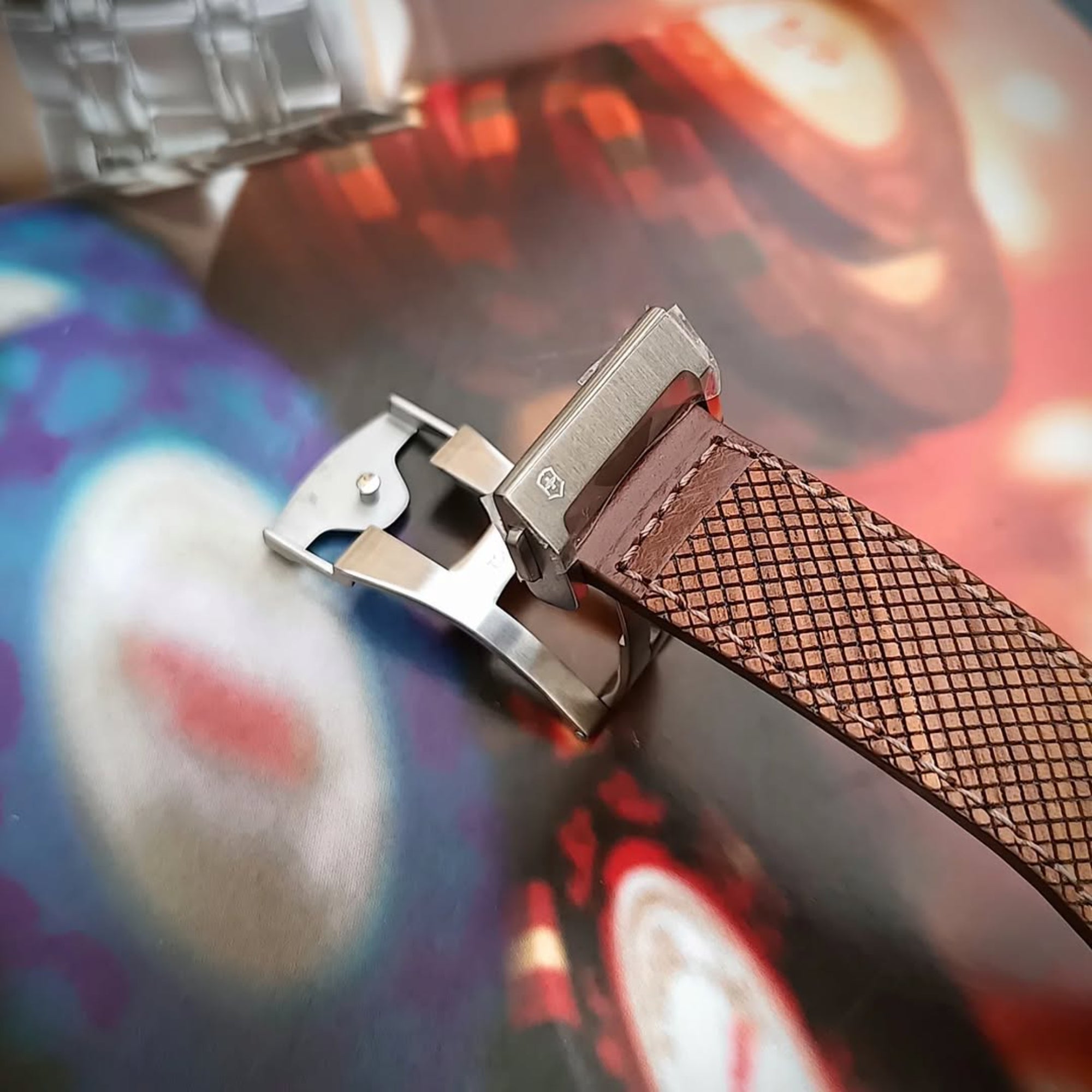 A close-up shot of a textured brown watch strap in, featuring an open stainless steel deployment clasp