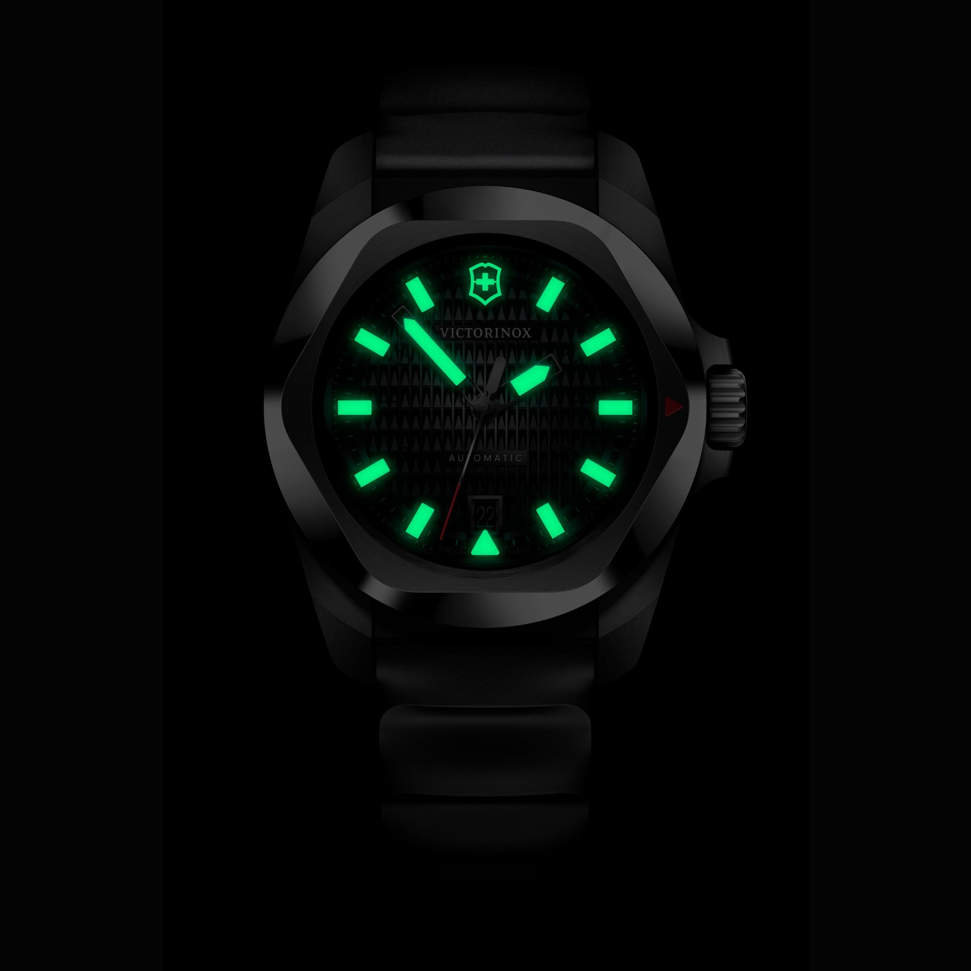 A dark close-up of a Victorinox I.N.O.X. watch, featuring green glowing lume