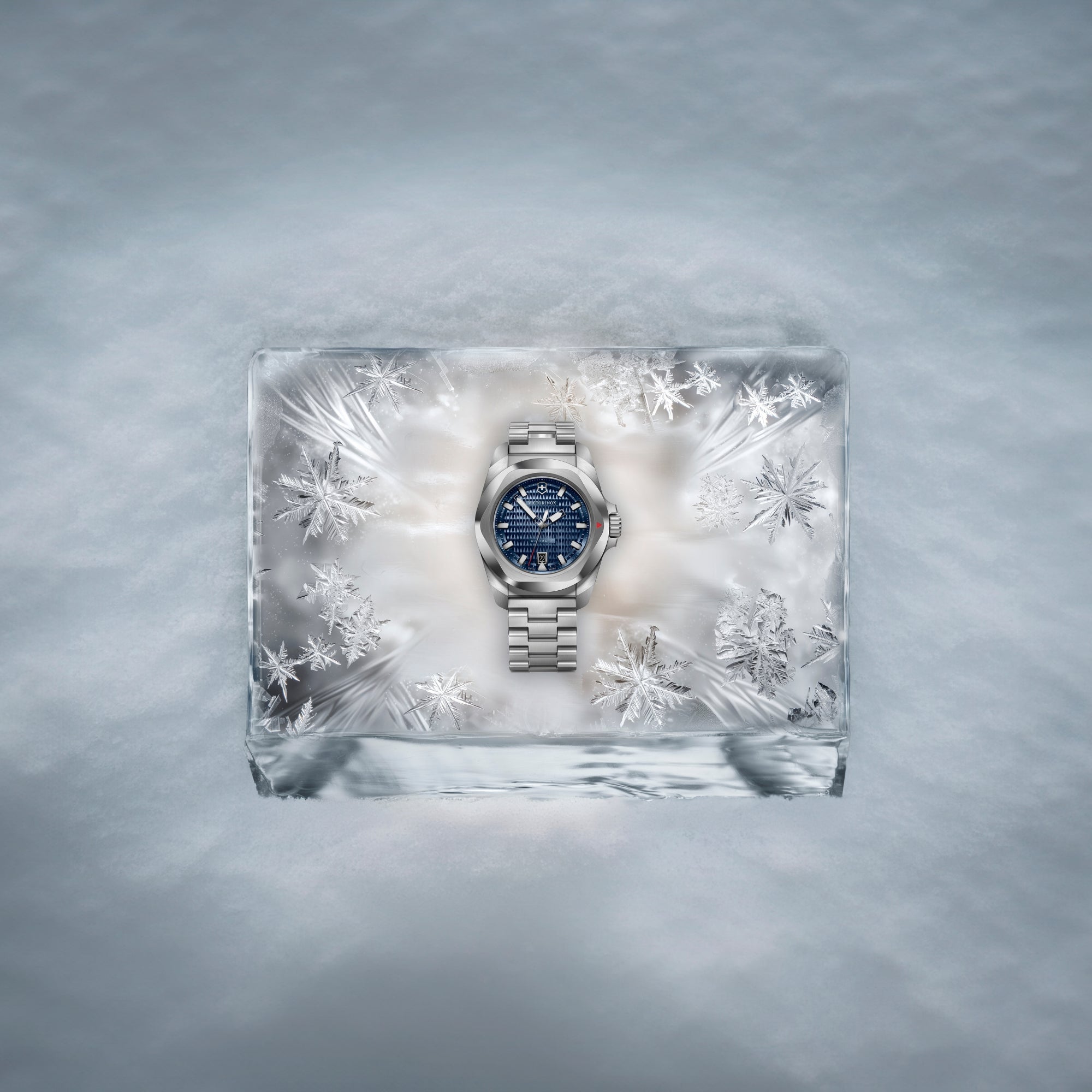 Victorinox I.N.O.X. blue dial automatic steel watch elegantly displayed on a transparent ice block surrounded by snowflakes in a frosty setting 