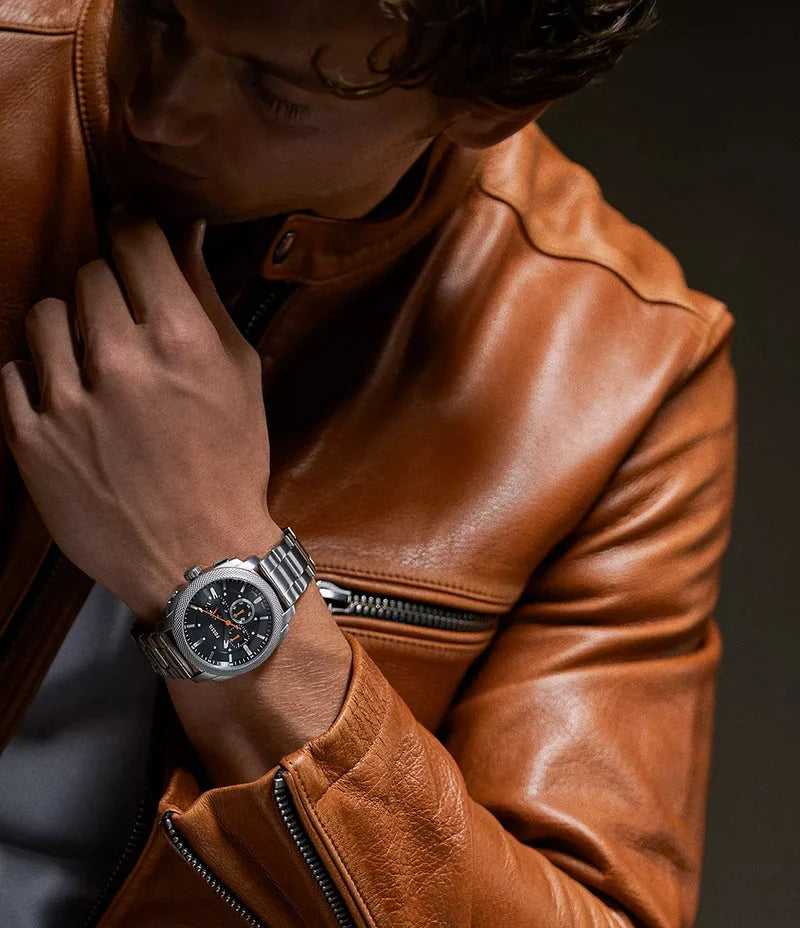 Fossil mens chronograph watch styled on wrist with black dial, textured bezel, and stainless steel link bracelet