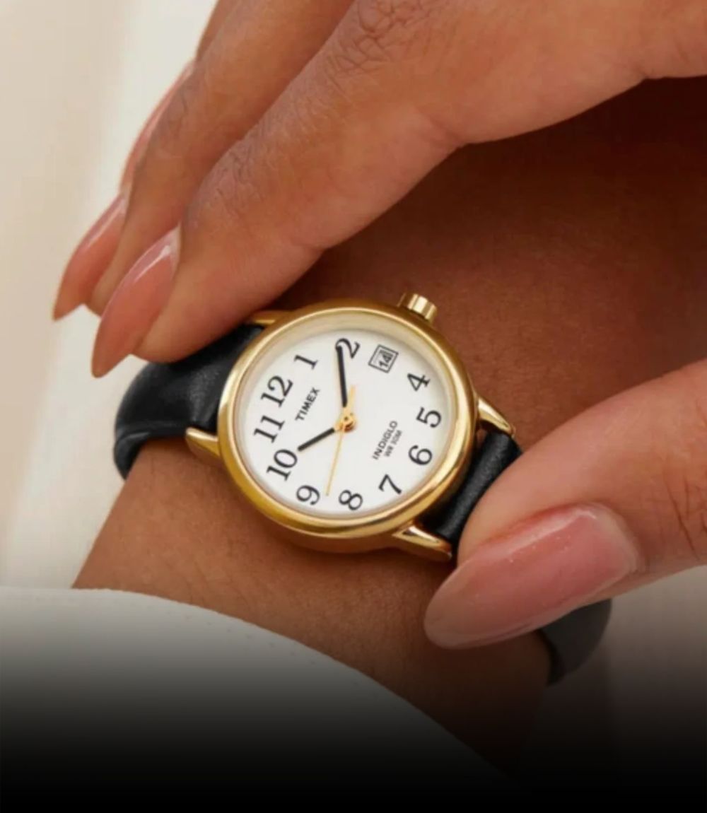 Timex Easy Reader watch with white dial, gold-tone case, and black leather strap shown on wrist