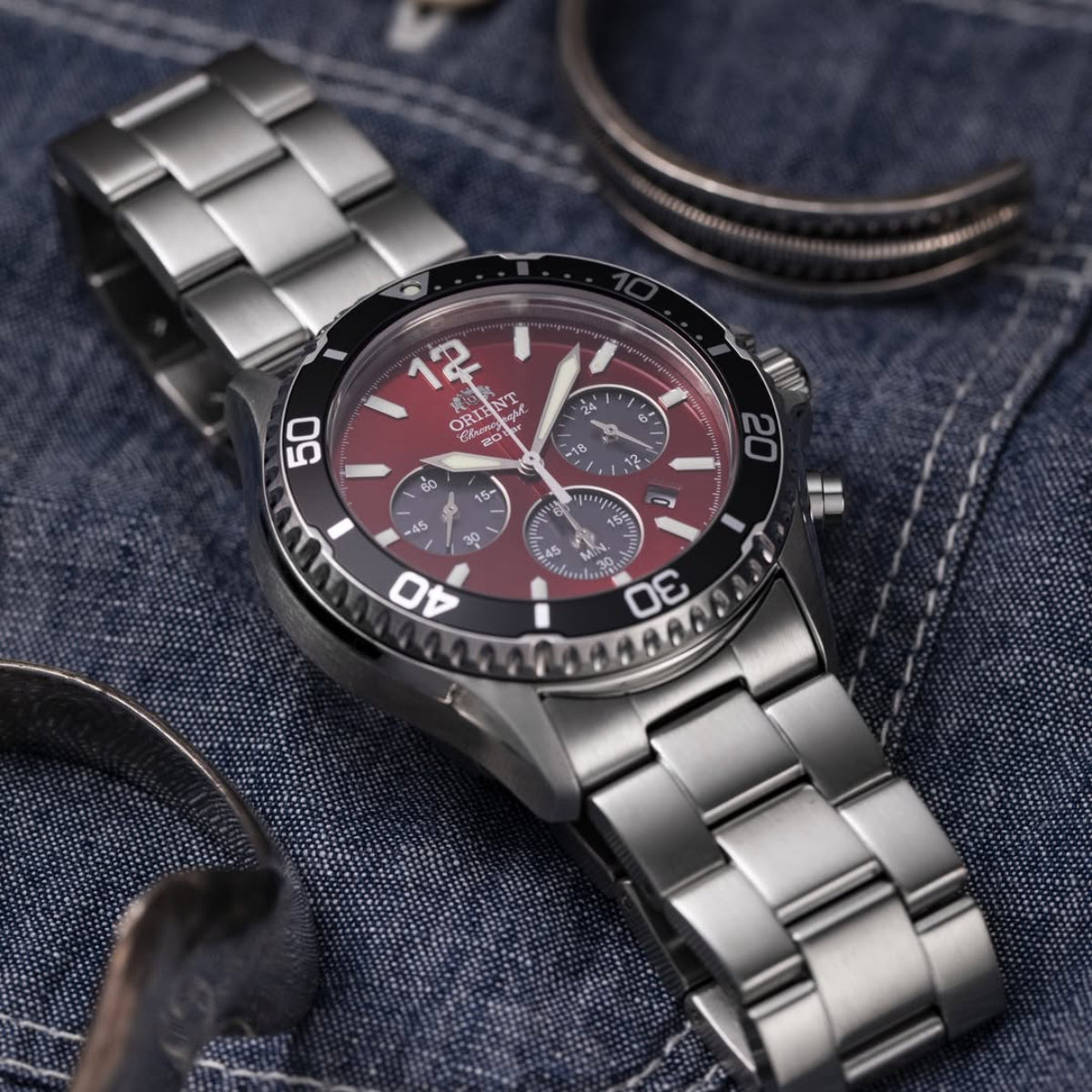 Orient Mako RA-TX0207R10B solar chronograph watch resting on blue denim fabric
