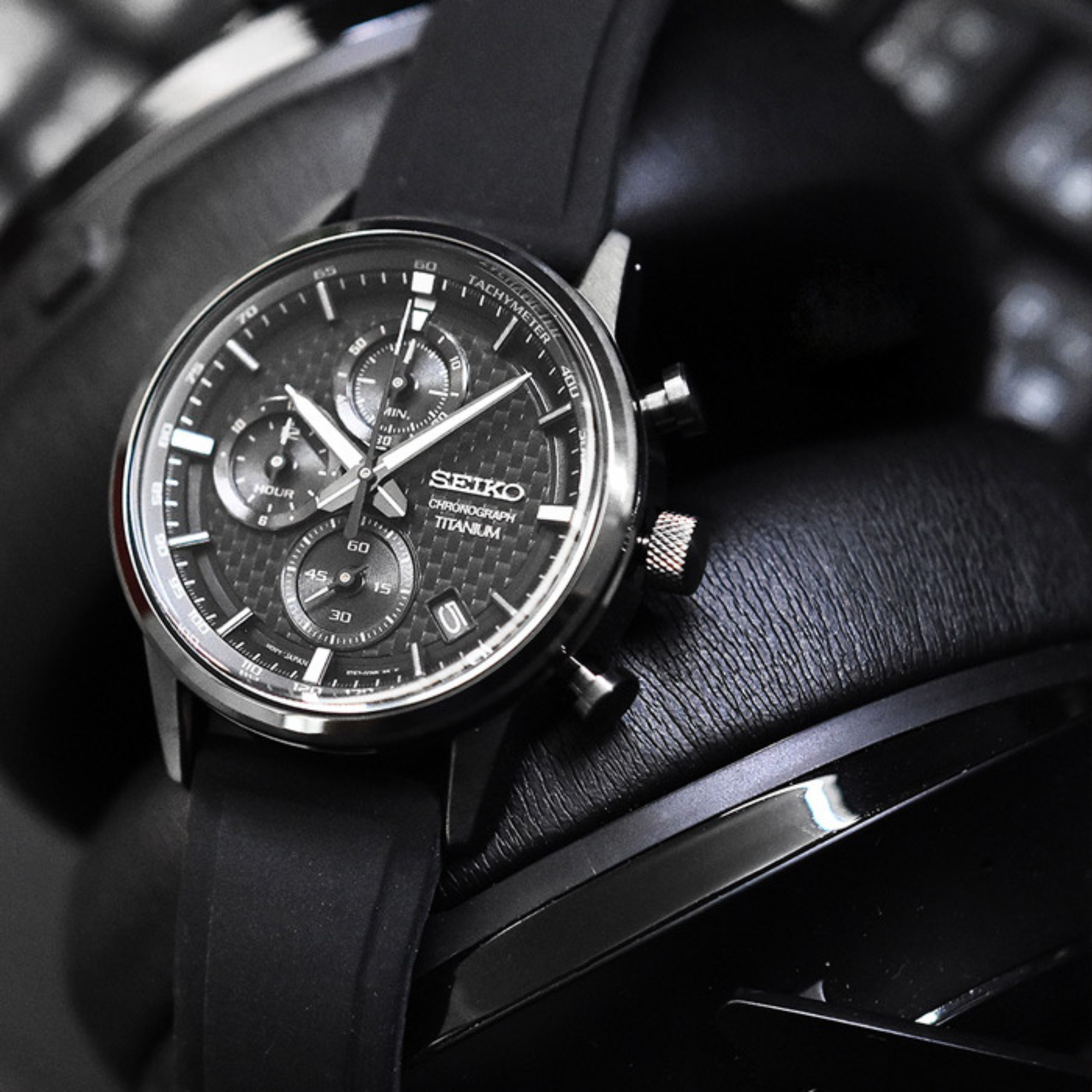 Black Seiko watch with detailed face on a black leather strap.