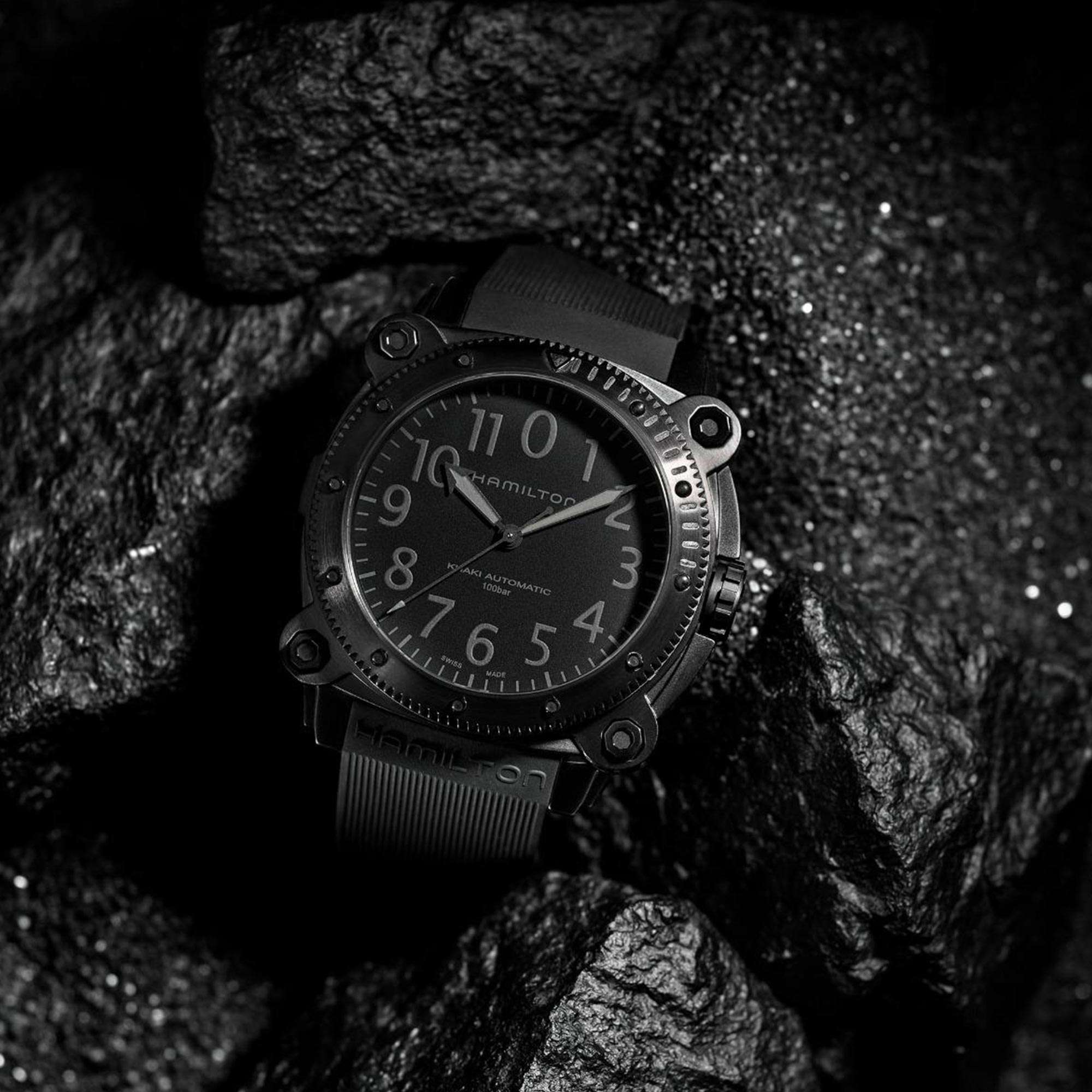 Hamilton Khaki Automatic black dive watch with black dial and rubber strap resting on dark wet rocks