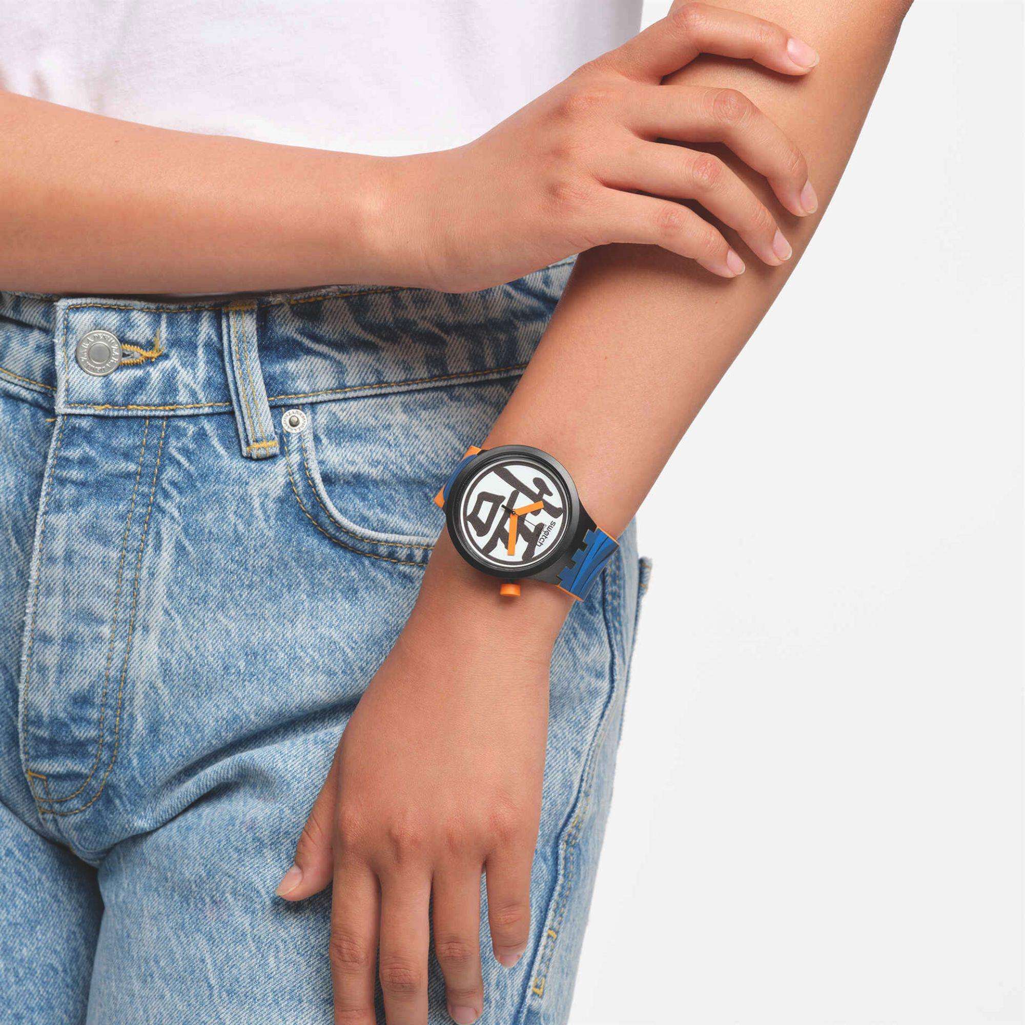 Person wearing a watch with a unique design on a plain background