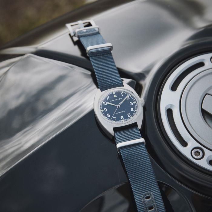 Hamilton mechanical field watch with a blue dial and matching blue NATO strap resting on a black surface