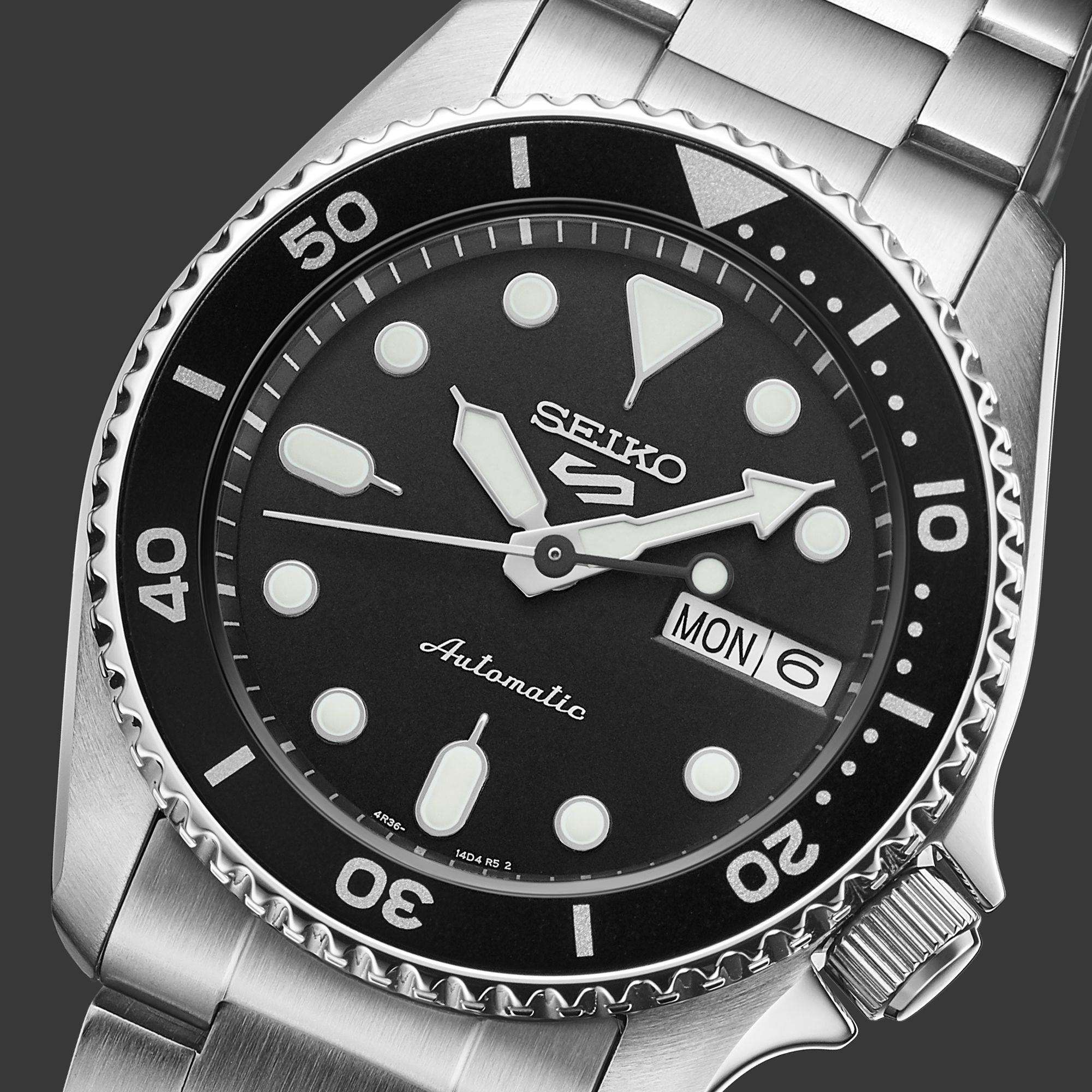 Seiko watch with black dial and silver metal strap on a dark background
