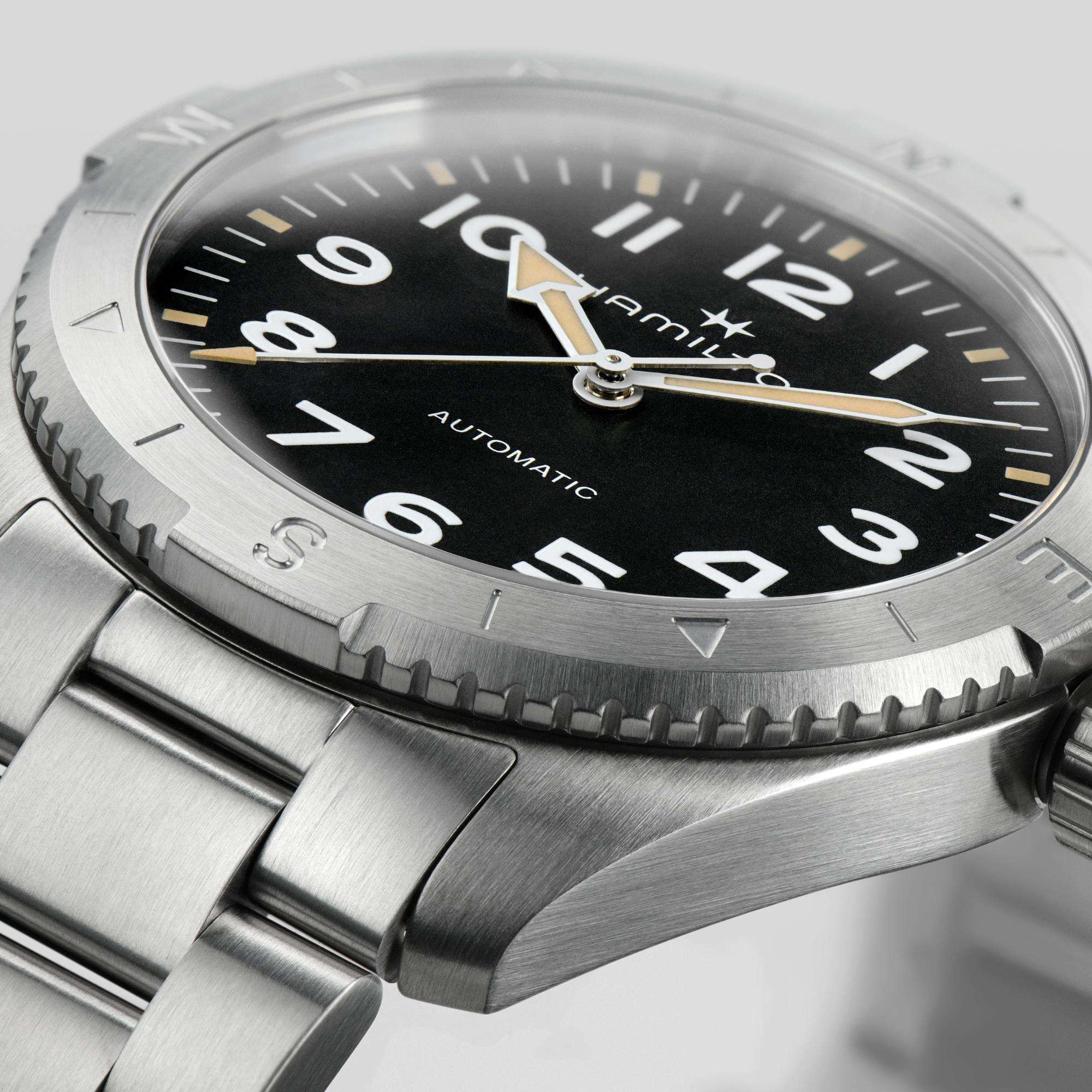 Close-up of a Hamilton automatic watch with a black dial, white numerals and under a brushed steel bezel