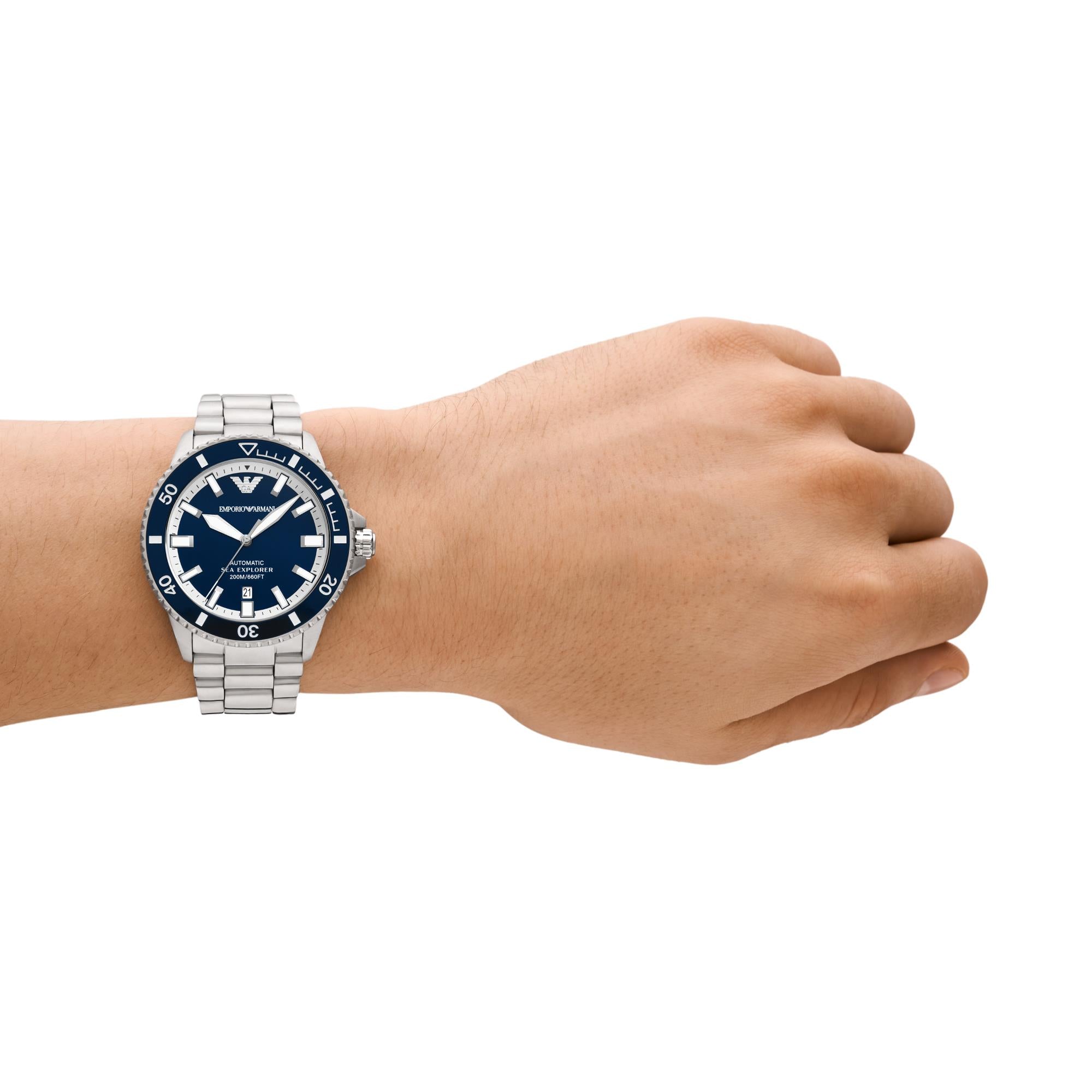 Hand wearing a silver watch with a blue face on a white background