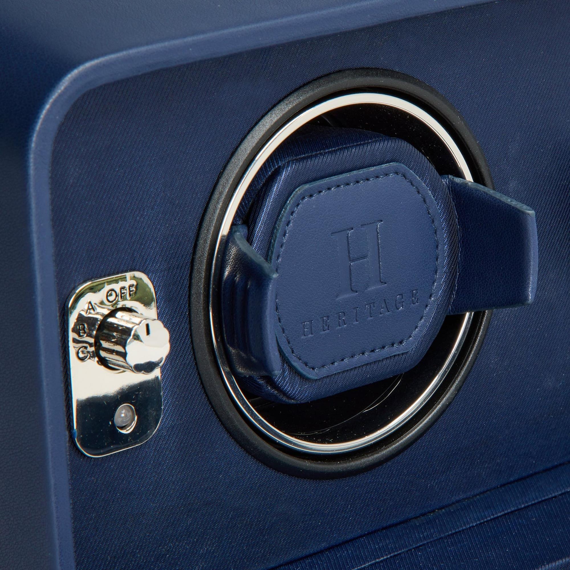 Close-up of a blue watch winder with a brand logo on a dark blue background