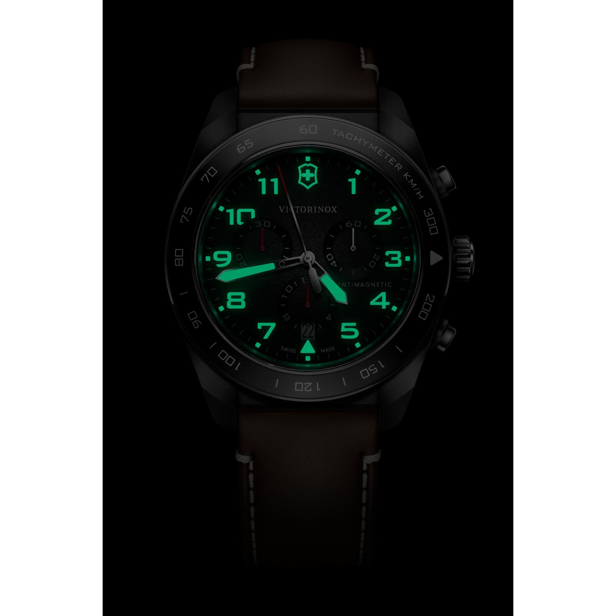 Victorinox Swiss Army 242046 chronograph watch with glowing green lume hands and markers on black dial in dark setting