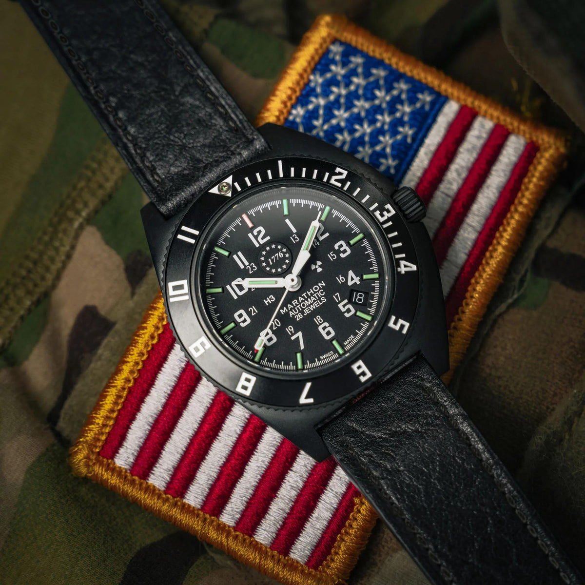 Marathon Navigator WW194030AN-US250 automatic watch resting on US flag patch showing black case and black dial