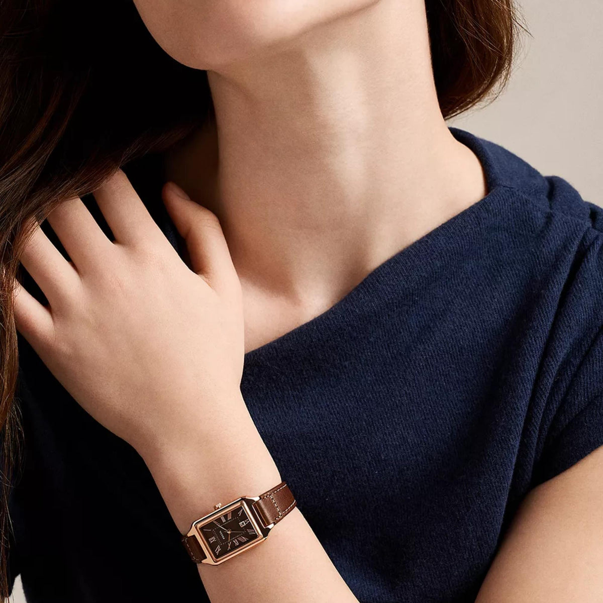 Fossil Raquel ES5503 mens wristwatch on wrist showing brown dial, rose gold-tone case, and brown leather strap paired with dark navy top