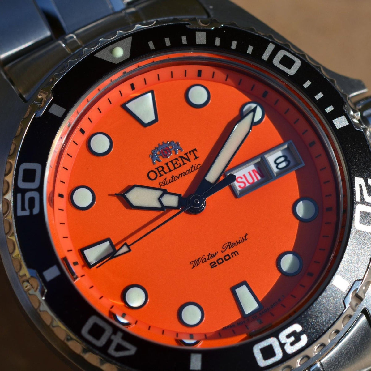 Orient Ray TAA02006M9 top view highlighting orange dial face, black bezel, and steel case