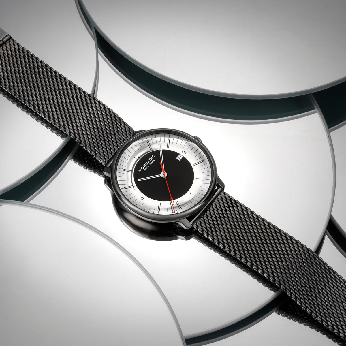 Mondaine Doppio Mirror MLE.41280.SM studio display view showing black dial watch positioned on mirrored circular panels