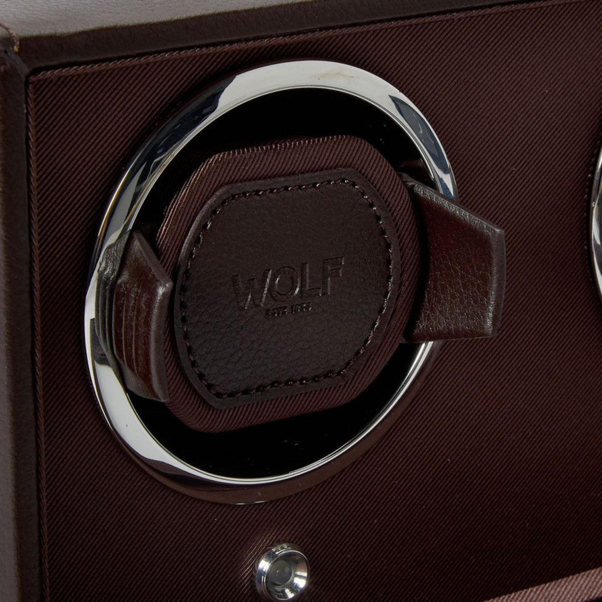 WOLF Cub 461206 close-up view highlighting brown leather watch cushion, chrome bezel ring, and debossed brand logo